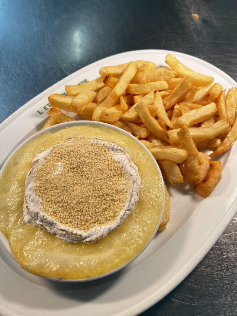 Fromage fondu crémeux avec Camembert gratiné et frites dorées sur assiette blanche. Texte 'L'ET DE' visible.